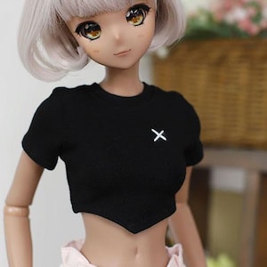 May include: A black crop top with short sleeves and a white "X" on the front. The top has a pointed hemline.