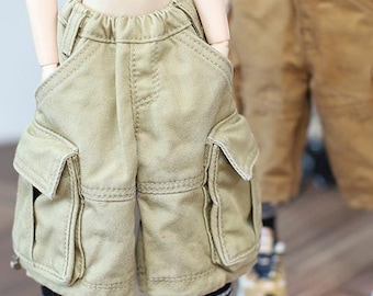 Puede incluir: Pantalones cortos cargo color beige con bolsillos laterales grandes y una cómoda cintura elástica. Los pantalones cortos están hechos de una tela duradera y presentan un estilo cargo clásico. Los pantalones cortos se muestran en una muñeca.