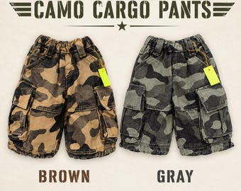 May include: Two pairs of Blythe stone-washed camo cargo pants, one in brown and one in gray. Each pair features an elastic waistband, belt loops, and two side cargo pockets with flaps. A small yellow tag is attached to each pair of pants.