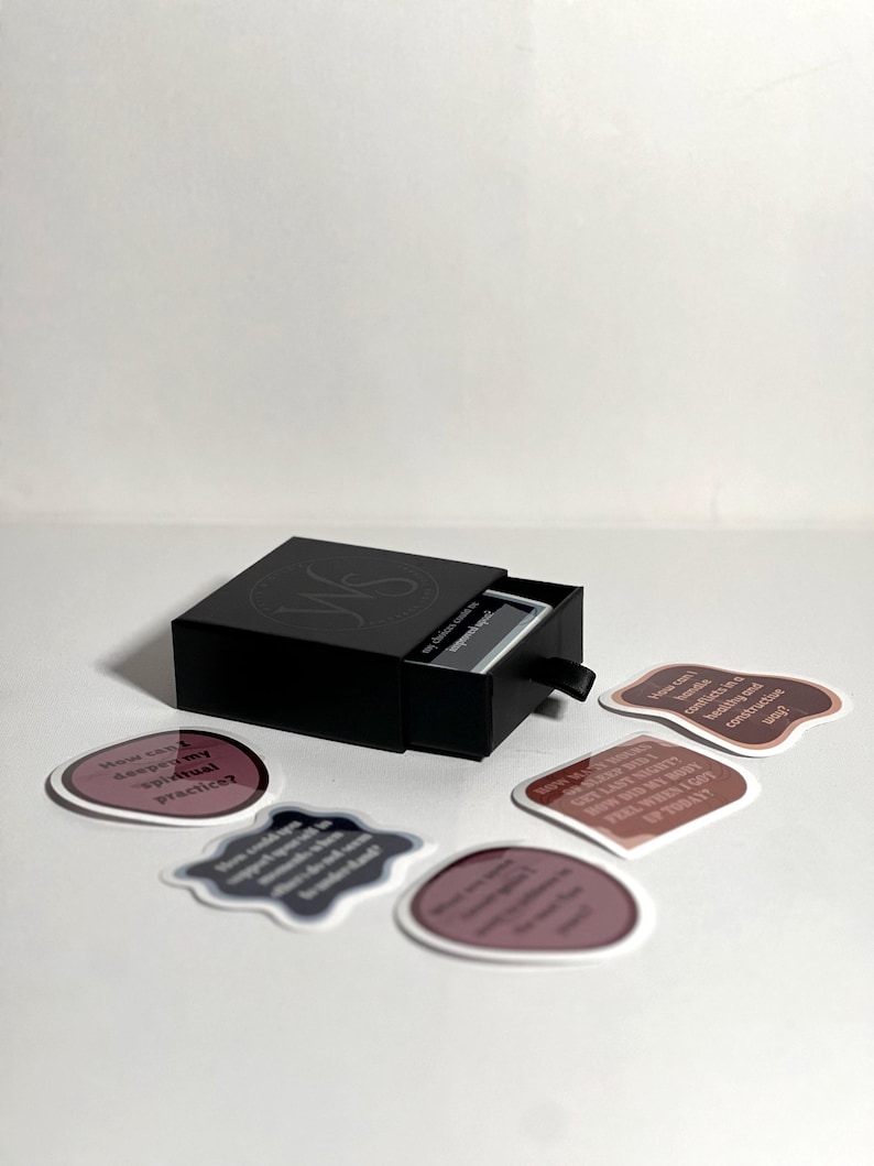 May include: A black box with a drawer that opens to reveal a set of affirmation cards. The cards are printed with inspirational quotes in a variety of colors and fonts. The box is labeled "My Choice Words" and "Journal & Affirmations".
