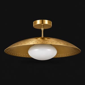 Può includere: Un lampadario da soffitto color ottone con un paralume traforato e un globo di vetro bianco di forma ovale. Il lampadario ha un design semplice ed elegante, perfetto per aggiungere un tocco di stile vintage a qualsiasi stanza.
