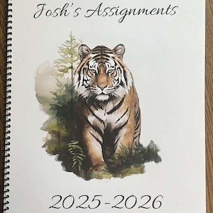 May include: A white binder with a watercolor illustration of a tiger in a forest setting. The binder has the text "Josh's Assignments" and "2025-2026" printed on it.