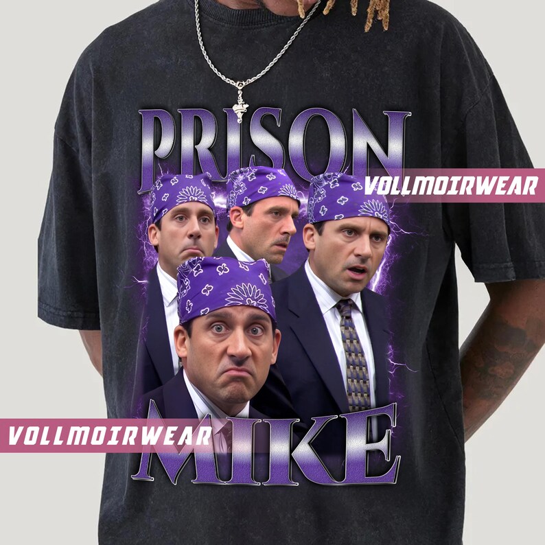 May include: Dark gray t-shirt featuring a graphic of a man wearing a purple bandana, with the word "PRISON" above and "MIKE" below. The shirt has the text "VOLLMOIRWEAR" on it.