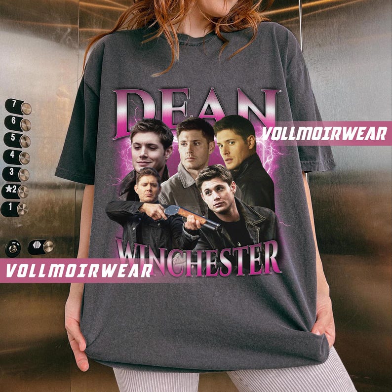 Puede incluir: Una camiseta gris oscura con un estampado gr&aacute;fico rosa de las palabras "Dean Winchester" e im&aacute;genes de cuatro hombres. El estampado gr&aacute;fico tiene una est&eacute;tica vintage.