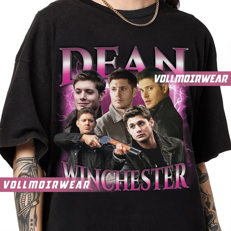 Puede incluir: Camiseta negra con un gr&aacute;fico rosa de las palabras "Dean Winchester" y cuatro caras de hombres. Los hombres visten ropa oscura y tienen el pelo oscuro. El gr&aacute;fico est&aacute; rodeado de rayos rosas.