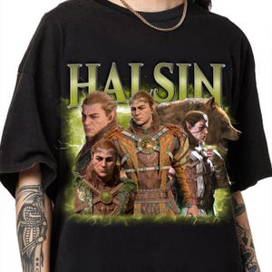 Puede incluir: Camiseta negra con un estampado gráfico de un grupo de personajes de un videojuego de fantasía. Los personajes están representados en un estilo estilizado, similar a un cómic. El texto "HALSIN" está impreso en letras grandes y en negrita sobre los personajes.