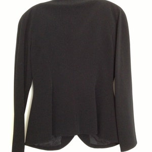 May include: A black blazer with a classic, tailored fit. The blazer has a single-breasted closure and long sleeves.