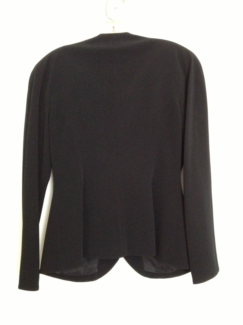 May include: A black blazer with a classic, tailored fit. The blazer has a single-breasted closure and long sleeves.