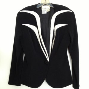 May include: A black blazer with white trim on the front and sleeves. The blazer has a single button closure.