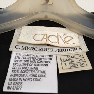 May include: White care label with black text detailing the fabric composition and care instructions for a black garment. The label reads "73% Triacetate/Triacetate 27% Polyester/Polyester Garniture Non Comprise Exclusive of Trimming Doublure/Lining 100% Acetate/Acetate Fabrique &agrave; Hong Kong Made in Hong Kong CA 02836 RN 67877". A smaller white label with black text shows size conversions for the garment: "USA 8 CAN 8 UK 10 GER 36".