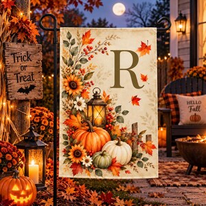 Peut inclure: Un drapeau de jardin rectangulaire orné d'une grande lettre R, de citrouilles orange et blanches, de tournesols, de baies rouges et d'une lanterne sur fond crème. Le motif inclut des feuilles d'automne et est fixé sur un support en métal.