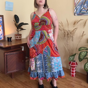 Könnte beinhalten: Ein Patchwork-Maxikleid mit V-Ausschnitt und Spaghettiträgern. Das Kleid hat eine lebendige Mischung aus Mustern in Rot, Blau und Orange mit einem Rüschensaum. Das Kleid ist aus leichtem Stoff gefertigt, perfekt für warmes Wetter.