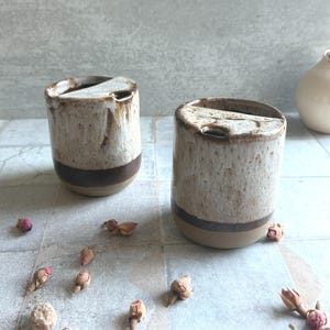 Detailed view of rustic glaze on pottery travel mug, showing melted marshmallow-inspired speckles and brown accents