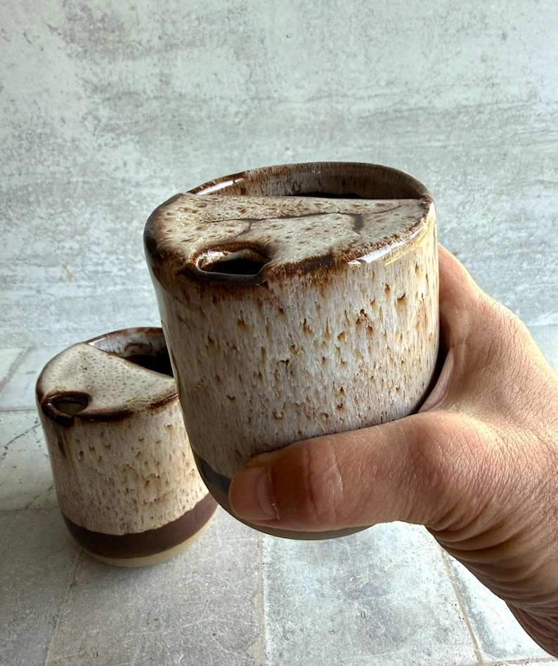 Close-up of toasted marshmallow glaze on handcrafted ceramic travel mug, highlighting speckled beige and white textures with brown toasted edges, from Claylicious pottery