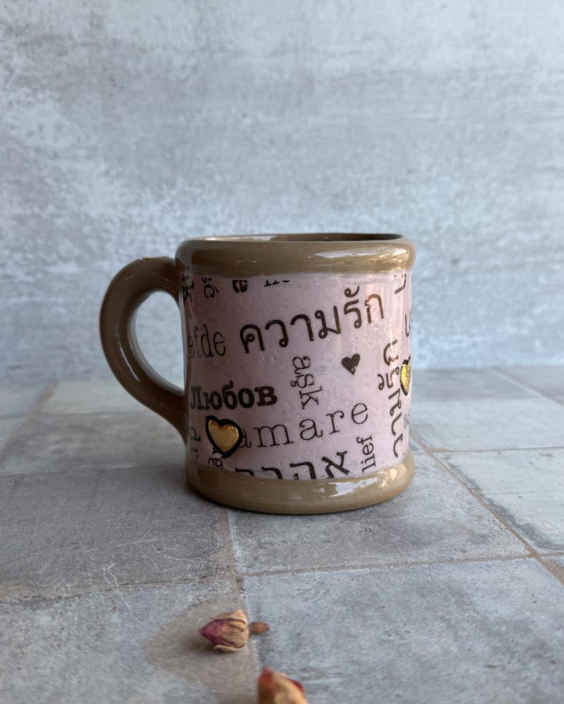 Handmade pottery coffee mug in violet tone with words of affection in various languages and 24k gold accent, plus dried rose props, ideal for galentines or relationship tokens