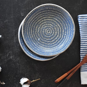 May include: Two blue and white ceramic bowls with a concentric circle pattern. The bowls are stacked on top of each other and are on a black surface.