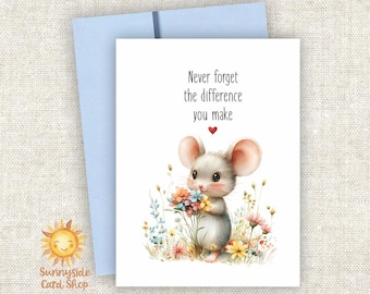 May include: A white greeting card with a light blue envelope featuring an illustration of a small mouse holding a bouquet of colorful flowers. The text reads, Never forget the difference you make, with a small red heart below the text.