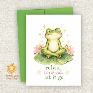 May include: A white greeting card featuring a green frog sitting in a lotus position on a lily pad, surrounded by pink lotus flowers and yellow sparkles. The text below reads: relax. unwind. let it go. A bright green envelope is tucked behind the card.