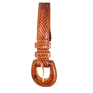 May include: A brown leather belt with a snakeskin pattern. The belt has a gold-colored buckle and several loops. The belt is shown against a white background.