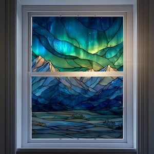 May include: A stained glass window depicting a landscape with mountains and an aurora borealis. The upper portion features vibrant blues, greens, and yellows, while the lower section showcases cooler blues and whites. The window is set within a white frame.