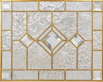 May include: A rectangular stained glass window with a gold-colored metal frame. The window features clear, textured glass panels in various shapes, including squares, rectangles, and diamonds. The central diamond shape has a shimmering, iridescent effect.