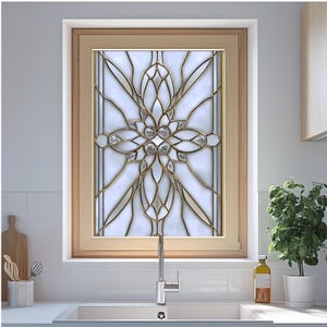 May include: A decorative stained glass window with a floral design. The window features a light wood frame, gold-colored metal accents, and clear glass elements. The design is symmetrical and geometric, with a white background.