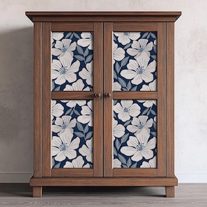 May include: A wooden cabinet with two doors featuring a floral pattern in shades of white and blue. The cabinet has a dark wood finish and a simple design.