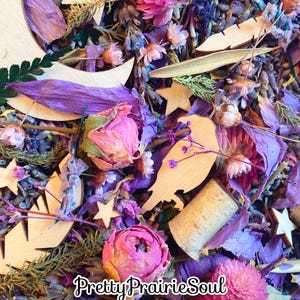 May include: A collection of dried flowers, herbs, and wooden shapes, including stars, moons, and birds, in shades of purple, pink, and brown. The wooden shapes are painted white. The text "Pretty Prairie Soul" is visible in the bottom right corner of the image.