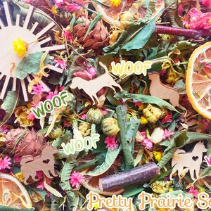 May include: A colorful mix of dried flowers, leaves, and wood shapes, including a sun, a lemon slice, and several dog silhouettes. The words "WOOF" are repeated throughout the image. The text "Pretty Prairie Soul" is at the bottom of the image.