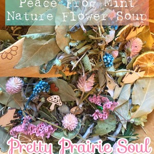 May include: A wooden bowl filled with dried flowers, leaves, and decorative elements. The arrangement includes pink, blue, and white flowers, along with wooden cutouts of a mushroom and a frog. The text "Peace Frog Mint Nature Flower Soup" and "Pretty Prairie Soul" are visible.