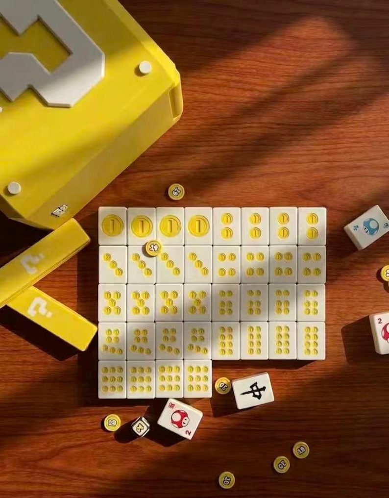 Puede incluir: Un juego de mesa con fichas blancas y s&iacute;mbolos amarillos, as&iacute; como una caja amarilla. Tambi&eacute;n hay monedas y dados amarillos, todo dispuesto sobre una superficie de madera.