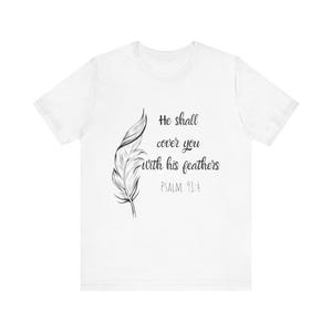 Könnte beinhalten: Ein weißes Kurzarm-T-Shirt mit einer schwarzen Strichzeichnung einer einzelnen Feder auf der linken Seite. Rechts neben der Feder steht der Text: He shall cover you with his feathers PSALM 91:4 in einer schwarzen Schreibschrift und serifenlosen Schrift.