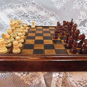 May include: A wooden chess set with a dark brown frame and a checkered board. The chess pieces are in two colors: light beige and dark brown. The pieces are arranged on the board, ready for a game.