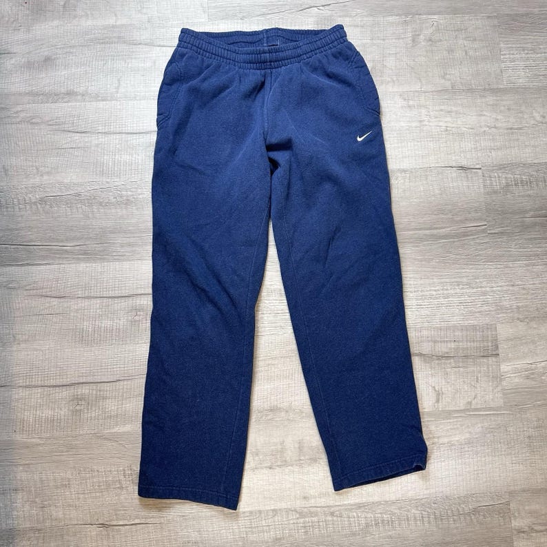 K&ouml;nnte beinhalten: Eine wei&szlig;e Keramik-Tasse mit schwarzem Henkel und dem handgeschriebenen Text "But First, Coffee". Die Tasse steht auf einer wei&szlig;en Oberfl&auml;che. F&uuml;r Hei&szlig;getr&auml;nke geeignet.