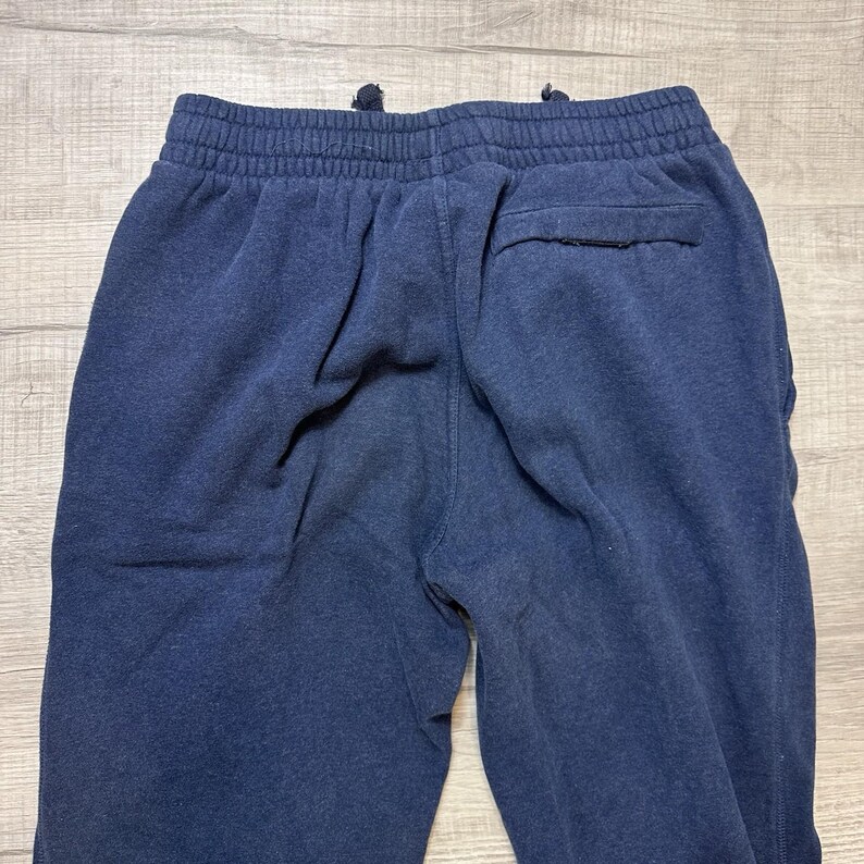 K&ouml;nnte beinhalten: Marineblaue Jogginghose mit elastischem Bund und Kordelzug. Die R&uuml;ckseite der Hose hat eine einzelne Tasche. Der Stoff scheint ein weiches, bequemes Material zu sein, das sich f&uuml;r Freizeitkleidung eignet.