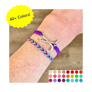 May include: Two bracelets are shown. One is a braided friendship bracelet with blue, pink, and purple threads. The other is a purple bracelet with a silver hockey stick charm. A yellow starburst graphic reads "40+ Colors!"