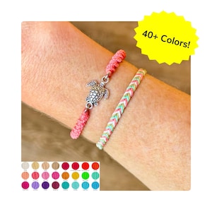 May include: Two bracelets are shown. One is pink with a silver turtle charm. The other is a braided pattern of green, pink, and white. A yellow starburst graphic reads "40+ Colors!" A color chart of available colors is shown.