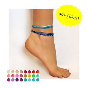 May include: Ankle bracelets in shades of blue and white are worn on an ankle. The image includes a color palette of over 40 colors. The text "40+ Colors!" is in a yellow starburst.
