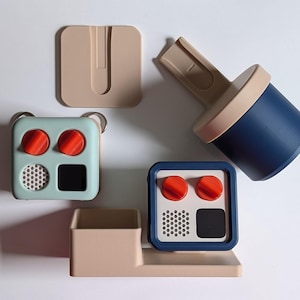 Peut inclure: Un assortiment d'organisateurs géométriques colorés dans les tons de bleu, beige et rouge. La collection comprend un conteneur carré avec des boutons rouges, un support cylindrique et un petit plateau rectangulaire. Les articles sont disposés sur une surface blanche.