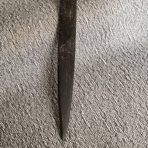 Puede incluir: Una herramienta de madera negra con un extremo puntiagudo y un pequeño agujero en la parte superior.