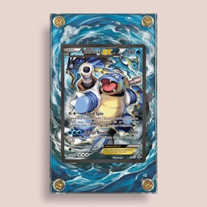 May include: A framed Blastoise EX Pokémon trading card. The card features a blue Blastoise character with the text "Rapid Spin" and "Splash Bomb". The frame has a blue water design and gold-colored corner accents.