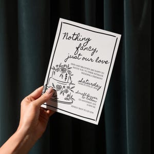 May include: A white wedding invitation with black text and a decorative border. The invitation includes the text "Nothing fancy, just our love" and details for the wedding ceremony, including the date, time, and location.