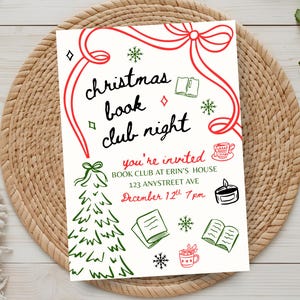 May include: A cream-colored invitation for a Christmas book club night, featuring red and green illustrations. The text reads "Christmas Book Club Night" and includes event details: date, time, and location. The invitation is on a woven placemat.