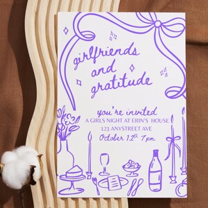 May include: White invitation card with purple illustrations and text. The card reads "girlfriends and gratitude" and invites guests to a girls' night at Erin's house on October 12th. Decorative elements include a bow, candles, and food illustrations.