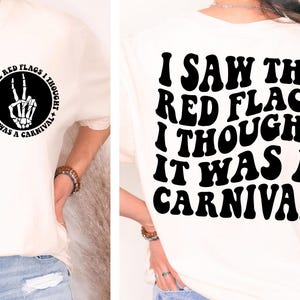 May include: White t-shirt with black text that reads "I saw the red flags I thought it was a carnival". The text is in a retro font style.