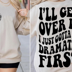 May include: A beige sweatshirt with black text that reads "I'll get over it I just gotta be dramatic first".