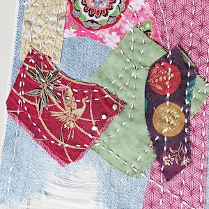 May include: A patchwork of fabric scraps sewn together with white thread. The fabrics are in various colors and patterns, including red, green, pink, and gold. The patchwork is a unique and creative way to use up scraps of fabric.
