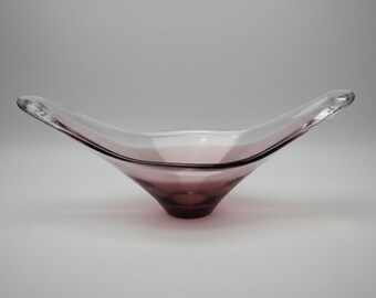 May include: A clear glass bowl with a flared, asymmetrical design. The bowl transitions from clear at the top to a deep purple at the base. The bowl has a smooth, polished surface and is likely used for decorative purposes.