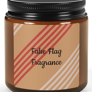 May include: A brown glass candle jar with a black lid. The label has red and white stripes and the text "False Flag Fragrance".