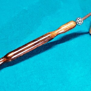 May include: A wooden mallet with a brown and black striped handle and a brown and black striped head. The handle has a silver bead at the end.